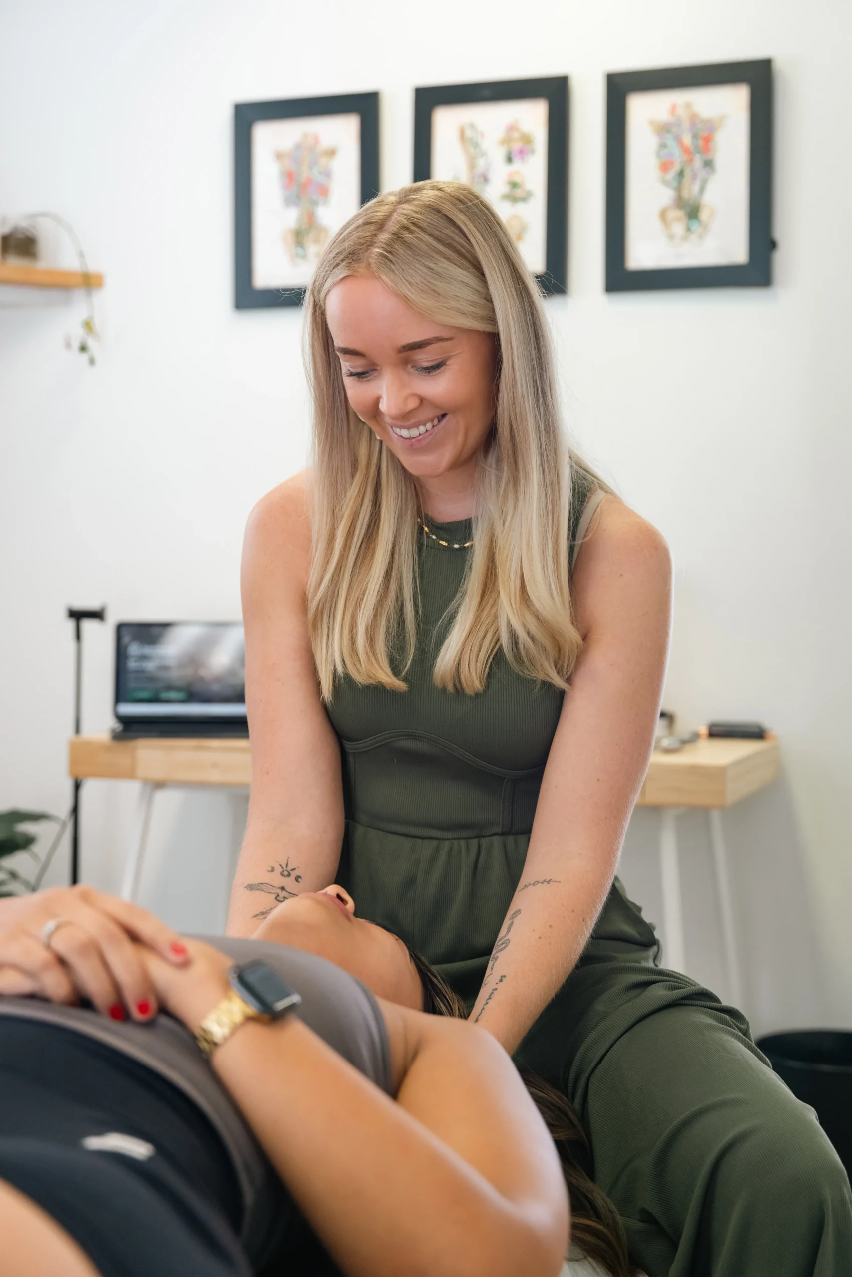 Dr Chelsea seated while smiling and helping patient with neck pain
